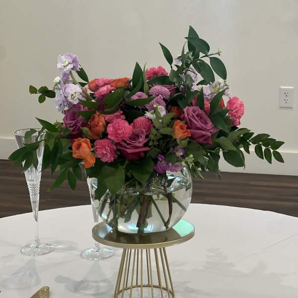 Colorful floral centerpiece in a glass bowl vase on a gold stand