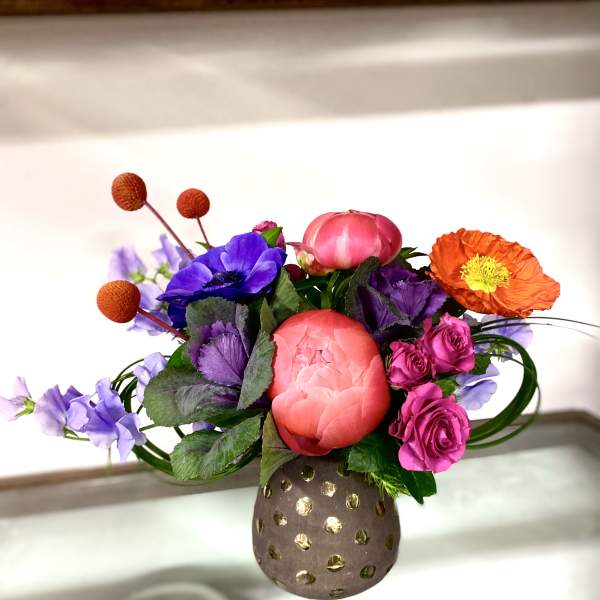 Colorful bouquet with pink, purple, and orange flowers in a dotted vase