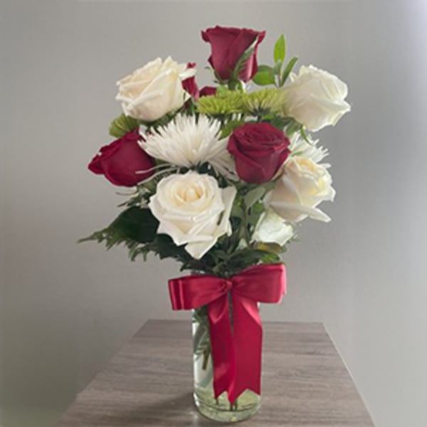 Bouquet of red and white roses in a glass vase with a red ribbon