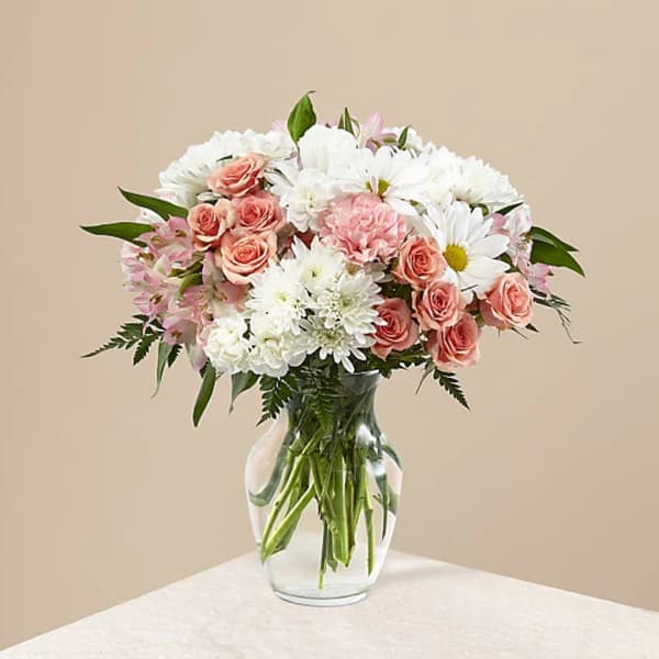 Pink roses and white daisies arranged in a clear glass vase