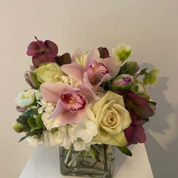 Bouquet of pink orchids and cream roses in a square glass vase