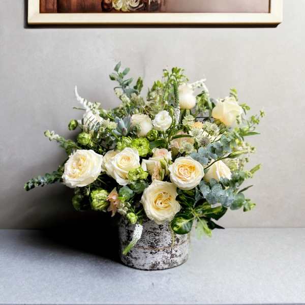 Cream roses in a rustic metal container with mixed greenery