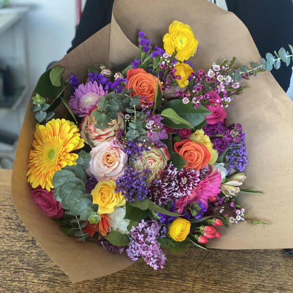 Mixed bouquet of colorful flowers wrapped in brown paper