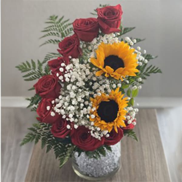 Red roses and sunflowers in a clear vase with baby's breath