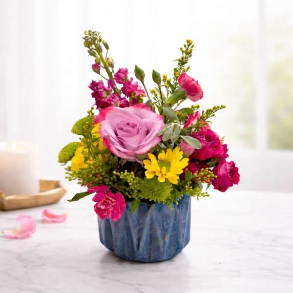 Pink and yellow flower arrangement in a blue ceramic pot