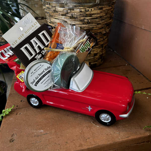 Gift basket in a red toy car with snacks and grooming items