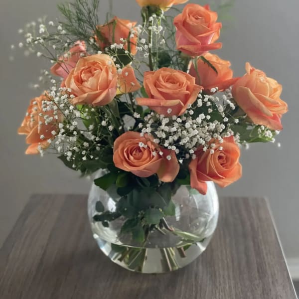 Peach roses arranged in a clear glass vase with baby's breath