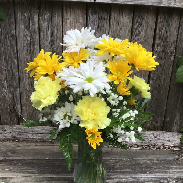 Yellow and white daisy bouquet in a glass vase