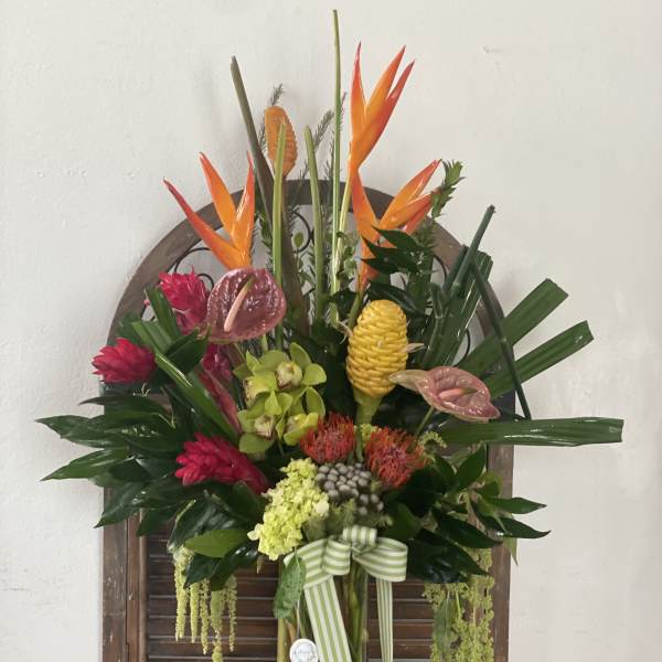 Tropical flower arrangement in a glass vase with orange bird-of-paradise and pink blooms