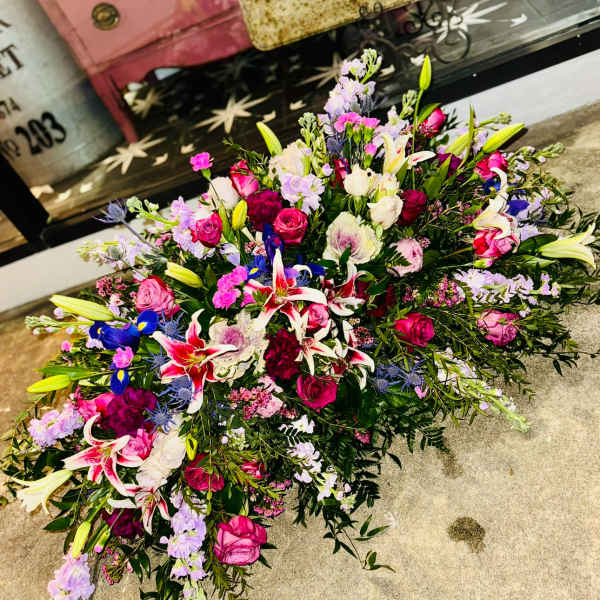 Large mixed floral spray with pink roses, lilies, and purple accents