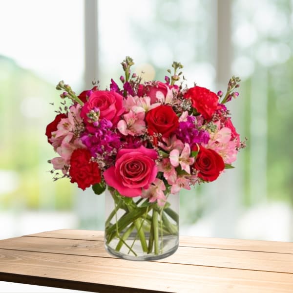 Bouquet of pink and red roses with small pink flowers in a glass vase