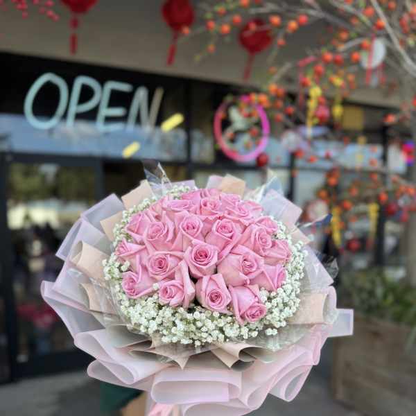 Bouquet of pink roses with white filler flowers and pastel wrapping