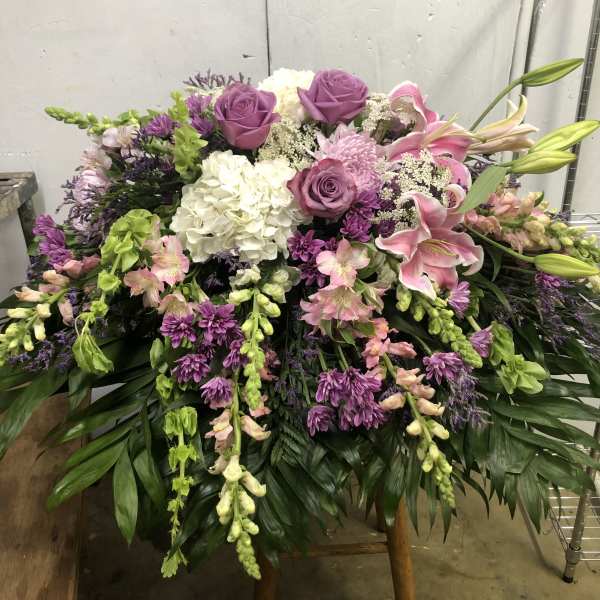 Large floral spray with pink lilies, purple roses, and white hydrangea