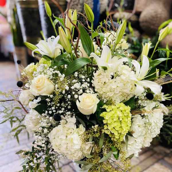 White lilies and roses arranged with hydrangeas in a vase