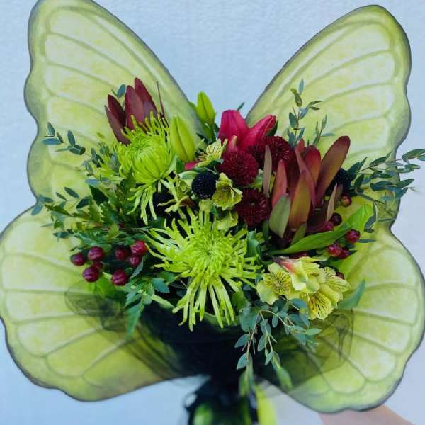 Bouquet with green and burgundy flowers in front of large translucent green wings