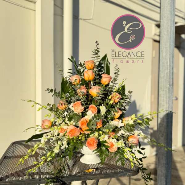 Tall peach rose arrangement in a white vase with trailing greenery