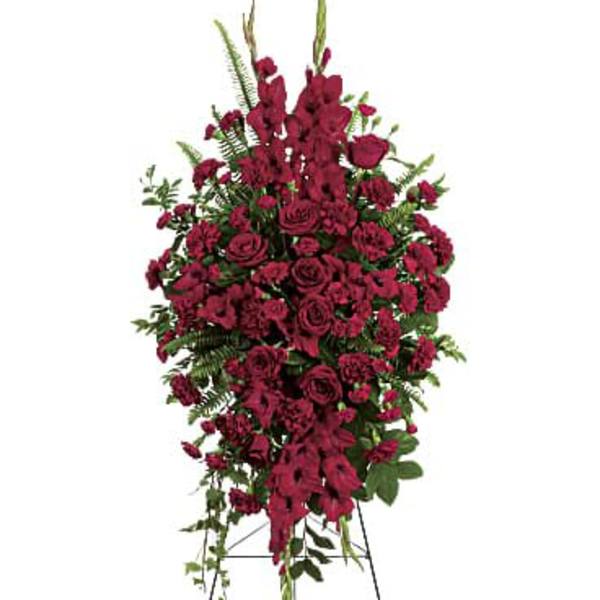 Tall standing spray of dark red roses and carnations on an easel