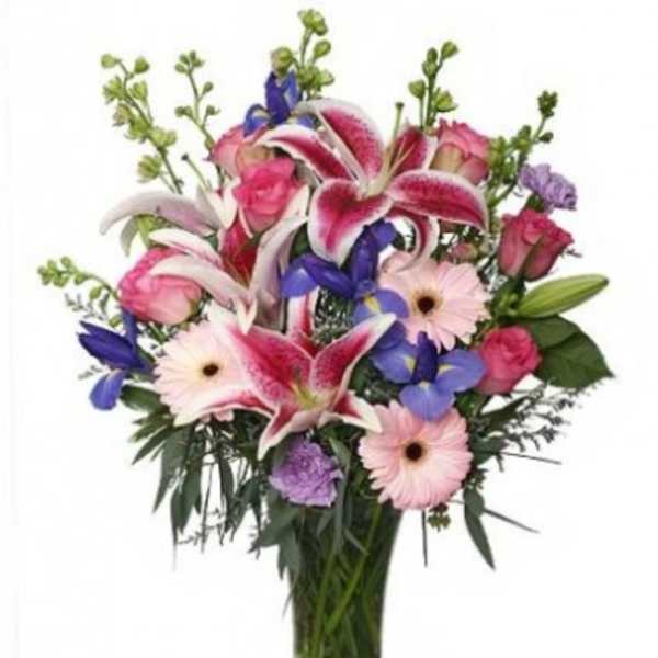 Mixed bouquet of pink lilies, roses, and gerbera daisies in a glass vase