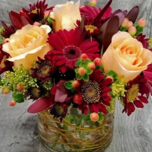 Bouquet of cream roses and deep red daisies in a glass vase
