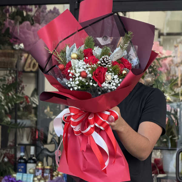 Bouquet of red roses wrapped in pink paper with a large ribbon