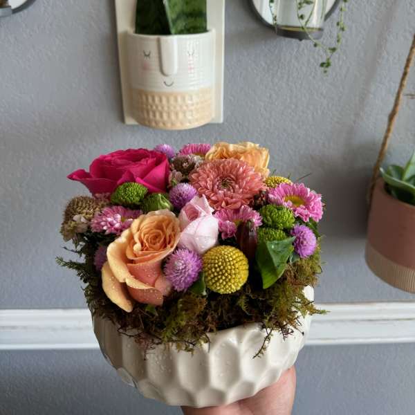 Compact bouquet of pink, peach, and yellow flowers in a white ceramic bowl