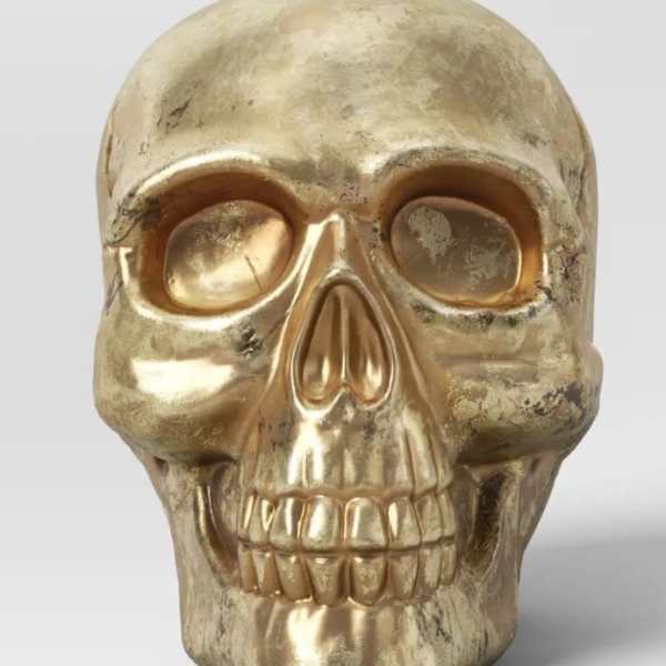 Gold skull decorative object on a plain background