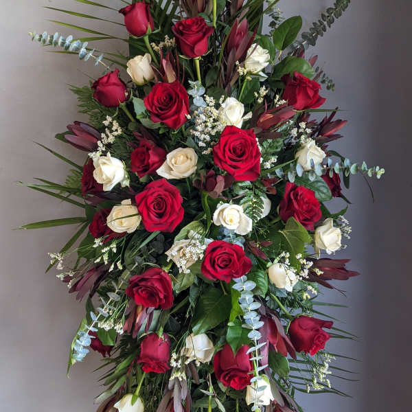 Tall standing spray of red and white roses with greenery