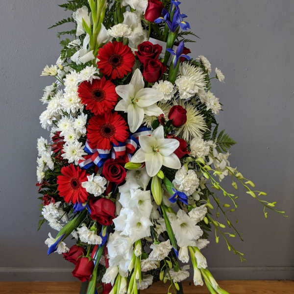 Standing floral spray with red, white, and blue flowers on a ribboned easel