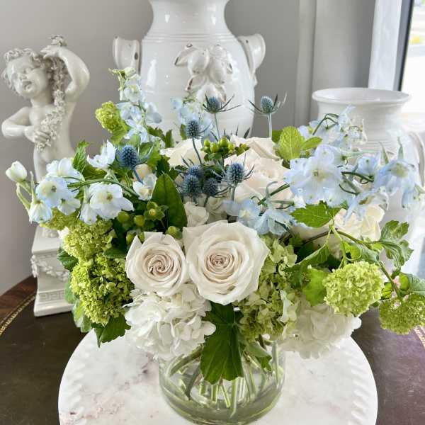White and blue floral arrangement in a clear glass vase
