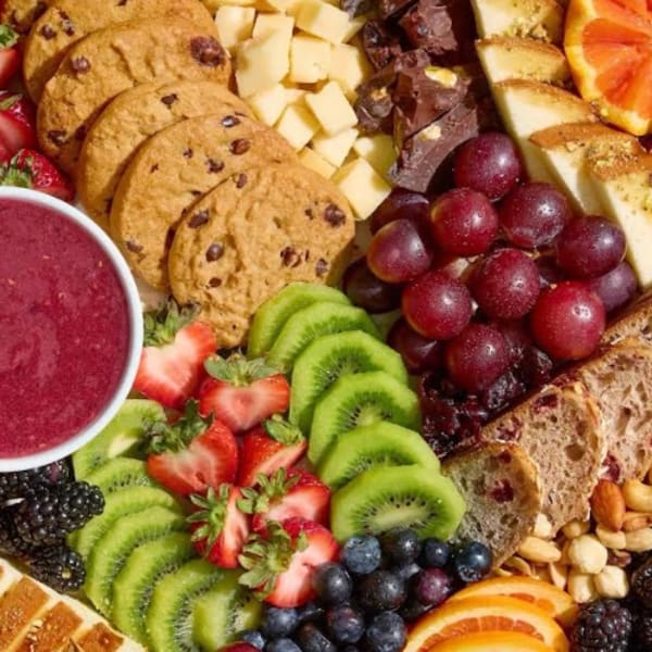 Fruit and snack platter with cookies, cheese, grapes, berries, and dip