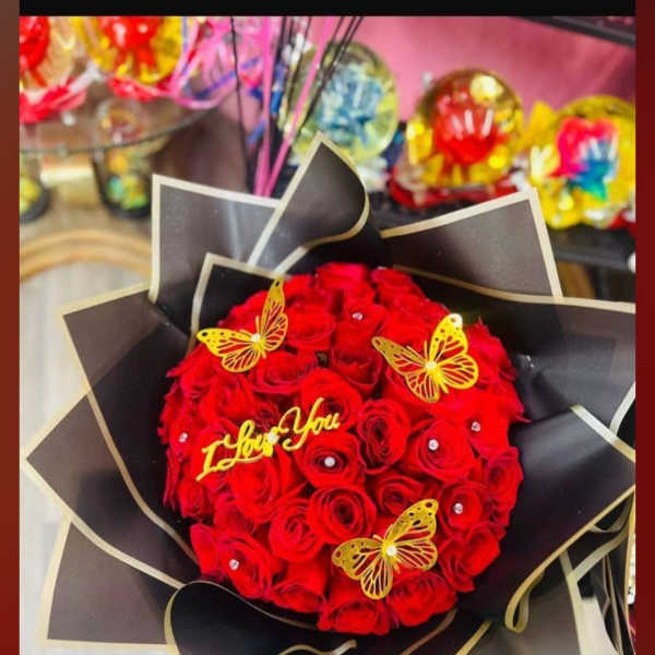 Bouquet of red roses wrapped in black paper with butterfly decorations