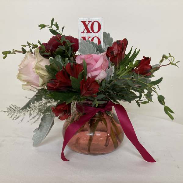 Bouquet of red and pink flowers in a glass vase with a ribbon
