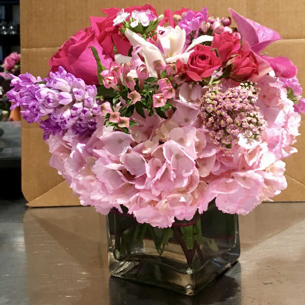 Pink and purple mixed bouquet in a square glass vase