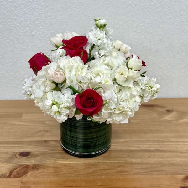Red roses and white hydrangeas arranged in a green vase