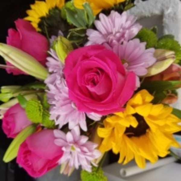 Bouquet of pink roses, yellow sunflowers, and lavender daisies