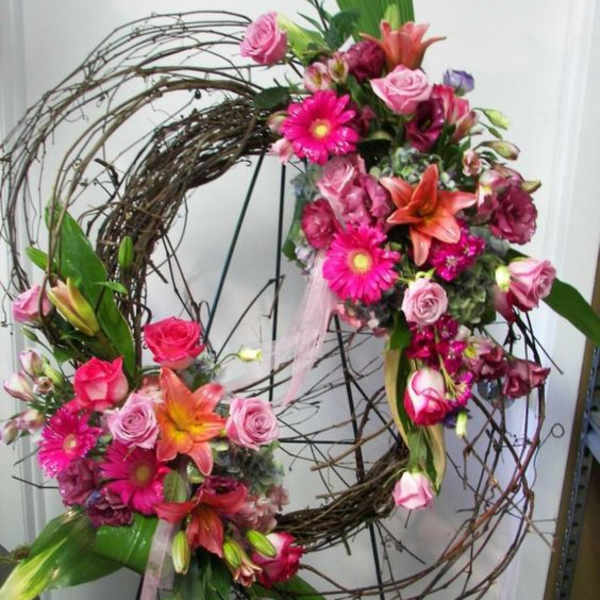 Two floral wreaths with pink and orange flowers on a wire frame