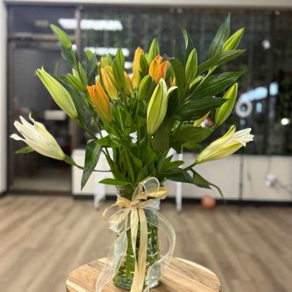 Bouquet of lilies in a glass vase with a gold ribbon