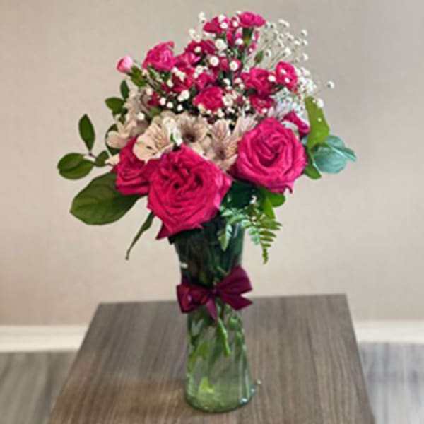 Pink roses and small white flowers in a glass vase