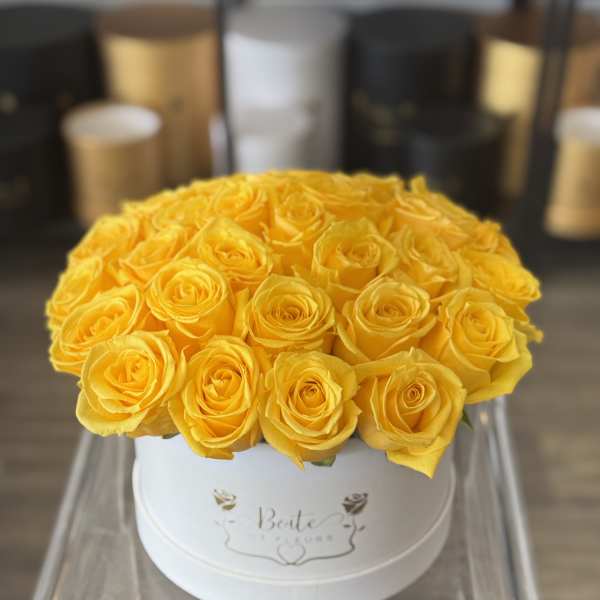 Yellow roses arranged in a white round box