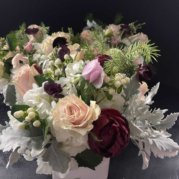 Compact floral arrangement with pink, white, and burgundy blooms in a white container