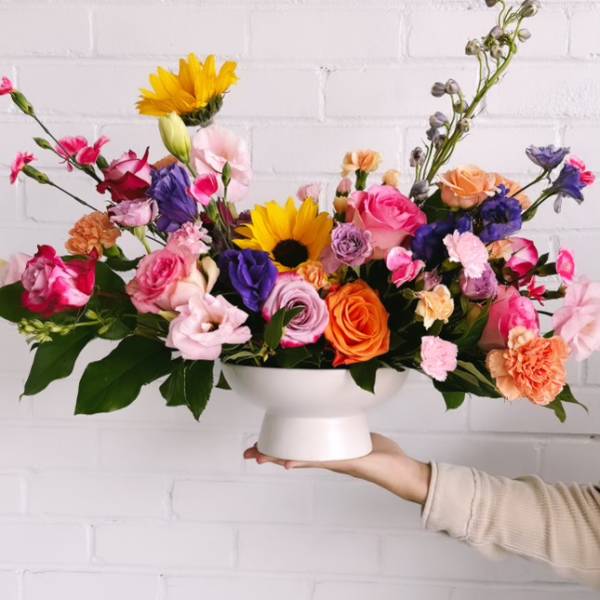 Colorful mixed flower arrangement in a white pedestal vase