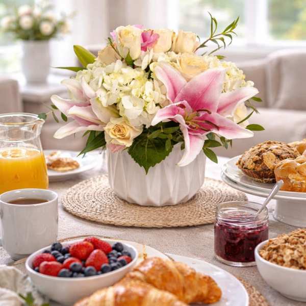 Pink lilies and cream roses in a white vase on a breakfast table