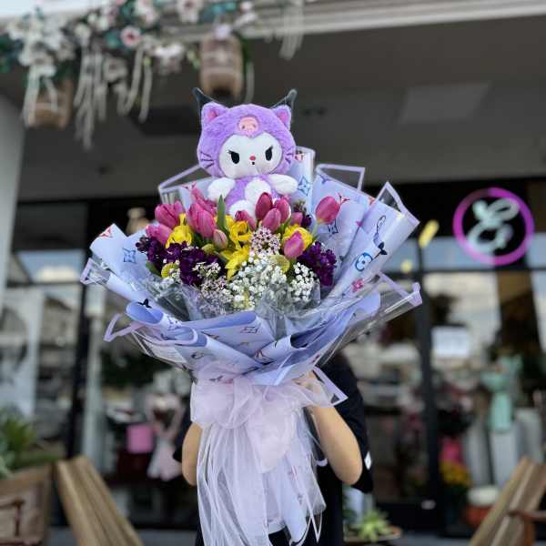 Bouquet of pink tulips and mixed flowers topped with a purple plush cat