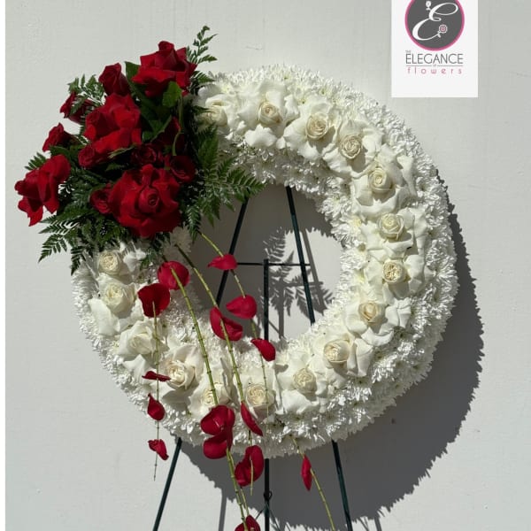 Circular floral wreath with red and white roses on a stand
