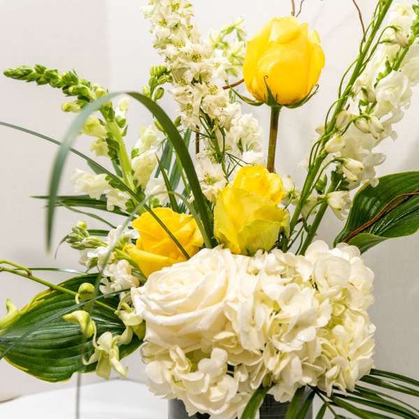 Yellow roses and white flowers arranged in a vase