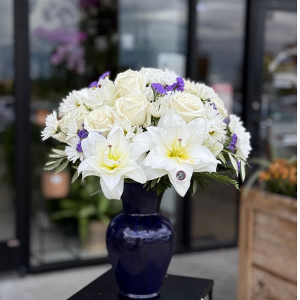 White roses and lilies arranged in a dark blue vase