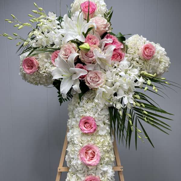 Large white floral cross with pink roses on an easel
