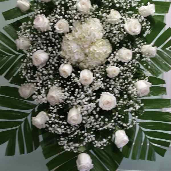 White rose and hydrangea funeral spray with palm leaves