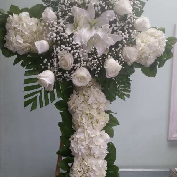 White floral cross arrangement with roses, lilies, and hydrangeas