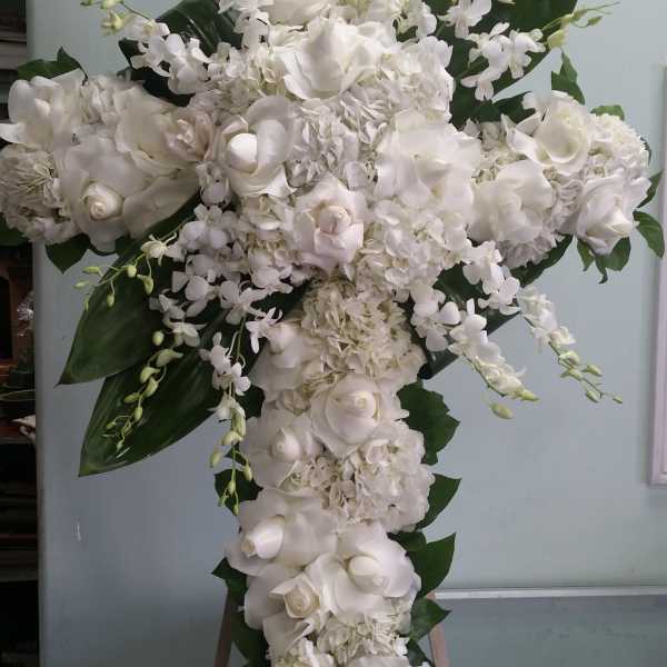 Large white floral cross arrangement with roses and orchids